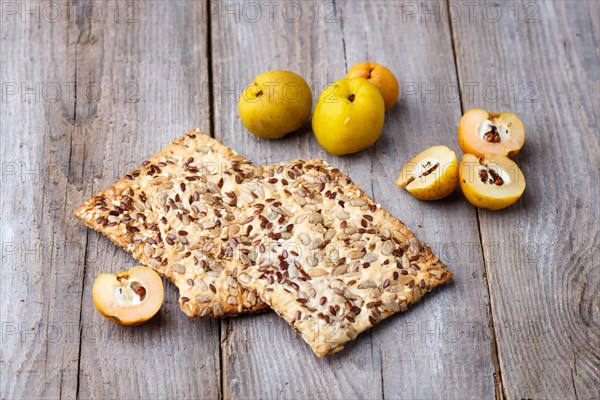 Biscuits with flax, sesame and sunflower seeds and yellow quince fruit on a rustic wooden