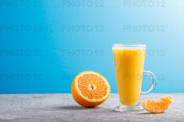 Glass of orange juice on a gray and blue background. Morninig, spring, healthy drink concept. Side