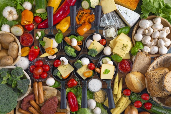 Filled raclette pans with a rich selection of cheese, vegetables and vegetarian meat substitutes,