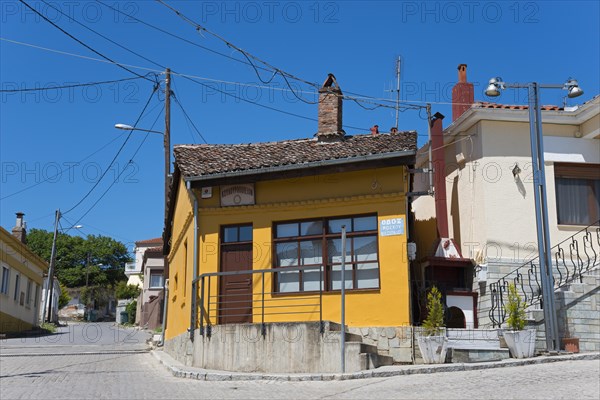 Small house with orange-painted facade and wooden windows on a quiet street, Soufli, Eastern