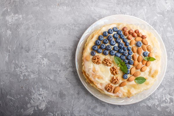 Homemade layered Napoleon cake with milk cream. Decorated with blueberry, almonds, walnuts,