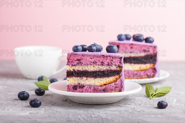 Homemade cake with souffle cream and blueberry jam with cup of coffee and fresh blueberries on gray