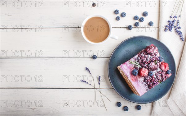 Berry cake with milk cream and blueberry jam on blue ceramic plate with cup of coffee and fresh