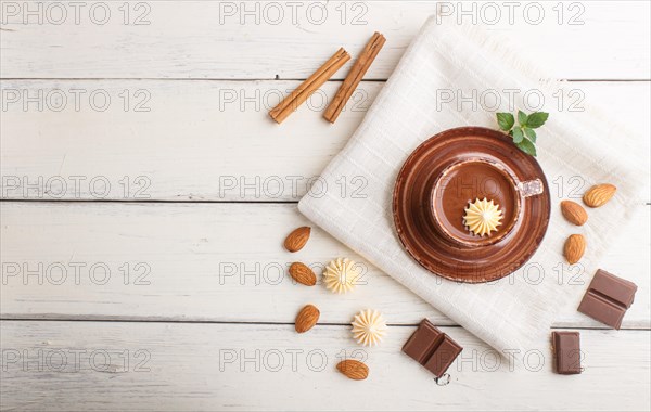 Cup of hot chocolate and pieces of milk chocolate with almonds on a white wooden background with