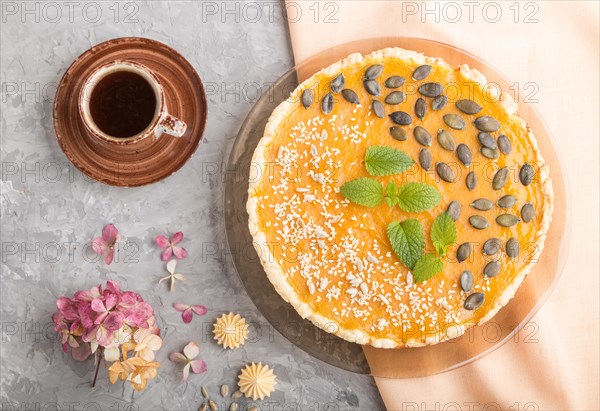 Traditional american sweet pumpkin pie decorated with mint, sesame and pumpkin seeds with cup of