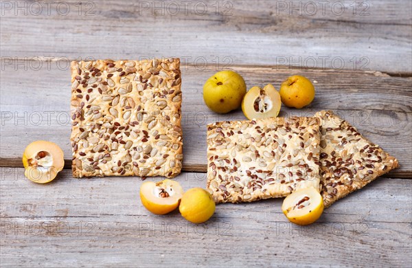 Biscuits with flax, sesame and sunflower seeds and yellow quince fruit on a rustic wooden