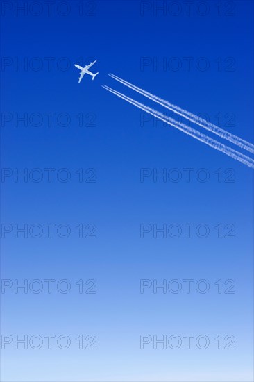 A passenger plane with vapour trails high in the blue sky