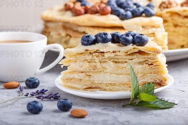 Homemade layered Napoleon cake with milk cream. Decorated with blueberry, almonds, walnuts,