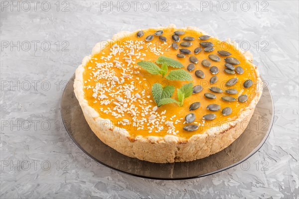 Traditional american sweet pumpkin pie decorated with mint, sesame and pumpkin seeds on a gray