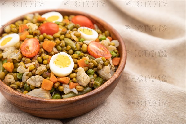Mung bean porridge with quail eggs, tomatoes and microgreen sprouts on a white wooden background