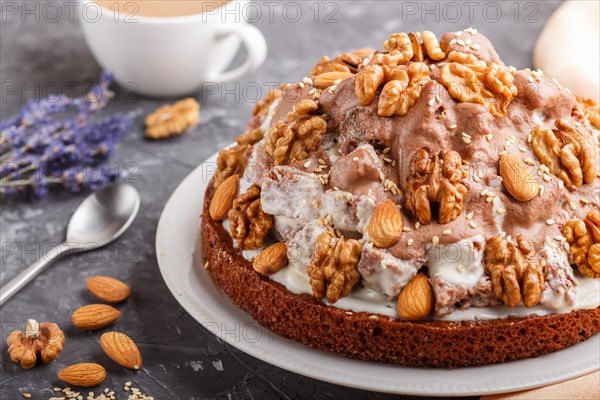 Homemade cake with milk cream, cocoa, almond, hazelnut on a black concrete background with orange
