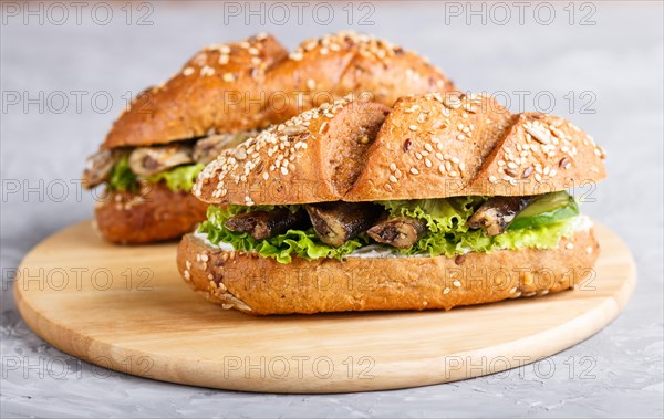 Sprats sandwiches with lettuce and cream cheese on wooden board on a gray concrete background. side