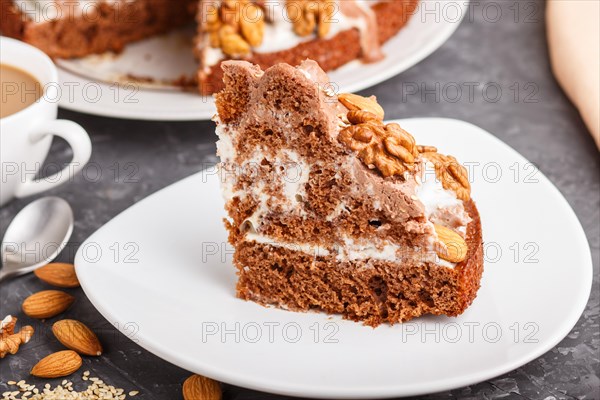 Homemade cake with milk cream, cocoa, almond, hazelnut on a black concrete background and a cup of