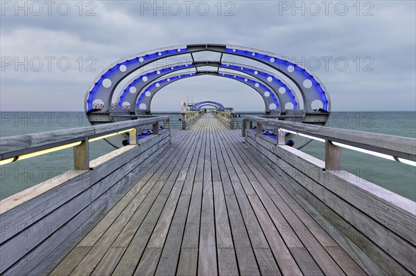 Long exposure of the Kellenhusen pier on the Baltic Sea with blue illuminated arcades