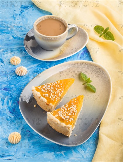 Two pieces of traditional american pumpkin pie with cup of coffee on a blue concrete background and