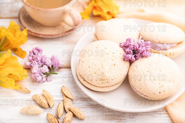 Meringues cakes with cup of coffee on a white wooden background and orange linen textile. Side
