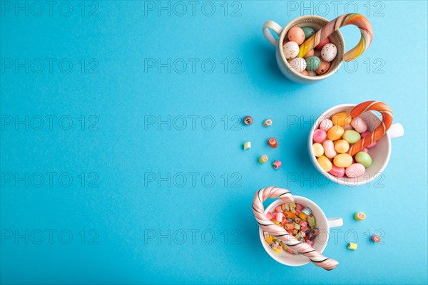 Heap of multicolored caramel candies in cups on blue pastel background. copy space, top view, flat