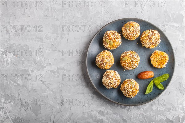 Energy ball cakes with dried apricots, sesame, linen, walnuts and dates with green mint leaves on a
