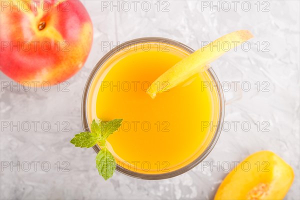 Glass of peach juice on a gray concrete background. Morninig, spring, healthy drink concept. Top
