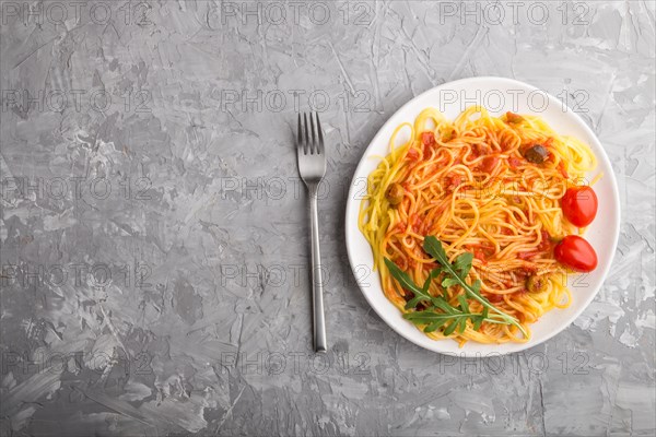 Corn noodles with tomato sauce and arugula on a gray concrete background. Top view, flat lay, copy