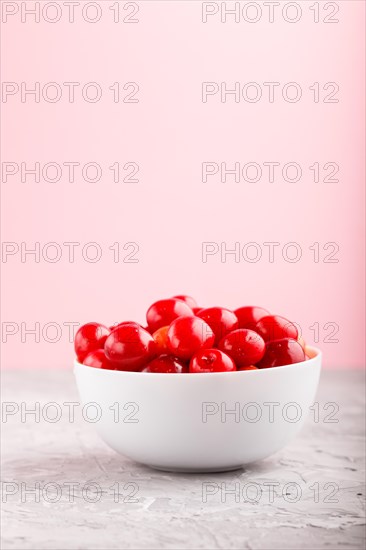 Fresh red sweet cherry in white bowl on gray and pink background. side view, close up, selective