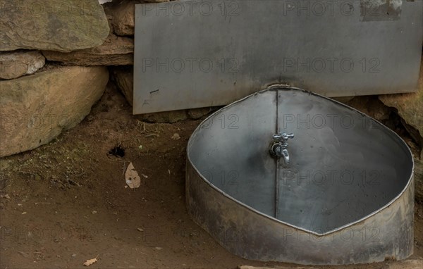 Public water faucet with metal basin located in mountain park for use by hikers visiting the area