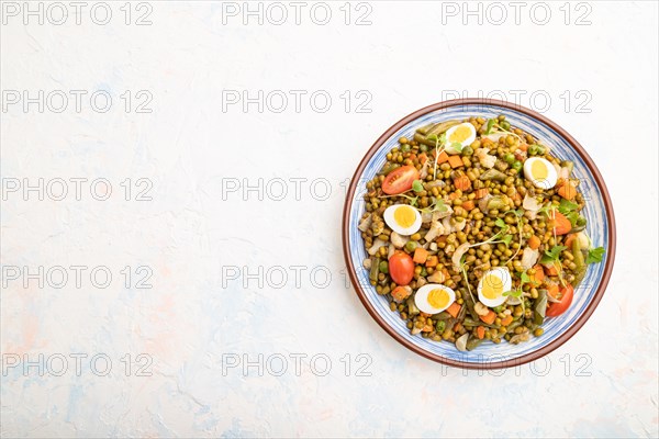 Mung bean porridge with quail eggs, tomatoes and microgreen sprouts on a white concrete background.