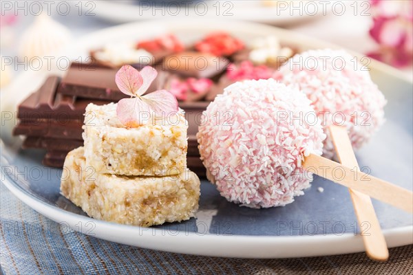 A pieces of homemade chocolate with coconut candies on a blue and brown textile. side view, close