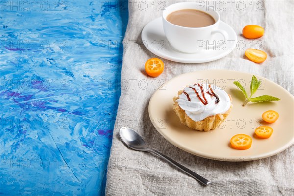 Cake with whipped egg cream on a light brown plate with kumquat slices and mint leaves on a blue