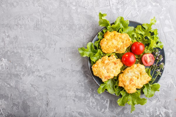 Minced chicken cutlets with lettuce, tomatoes and herbs on a gray concrete background. top view,