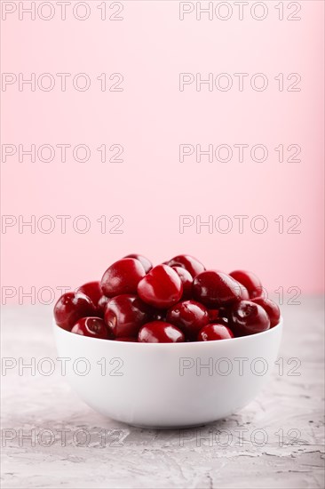Fresh red sweet cherry in white bowl on gray and pink background. side view, close up, selective