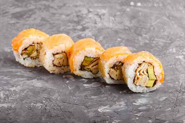Japanese maki sushi rolls with salmon, avocado and omelette on black concrete background. Side