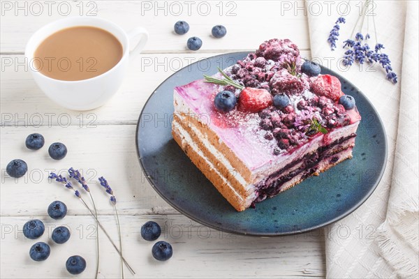 Berry cake with milk cream and blueberry jam on blue ceramic plate with cup of coffee and fresh