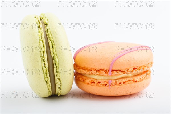 Orange and green macarons or macaroons cakes isolated on white background. side view, close up,