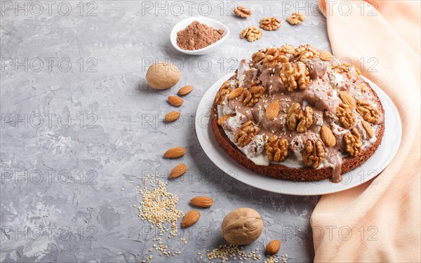 Homemade cake with milk cream, cocoa, almond, hazelnut on a gray concrete background with orange