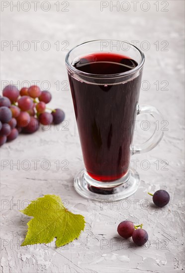 Glass of red grape juice on a gray concrete background. Morninig, spring, healthy drink concept.