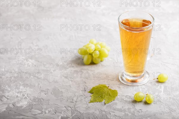 Glass of green grape juice on a gray concrete background. Morninig, spring, healthy drink concept.