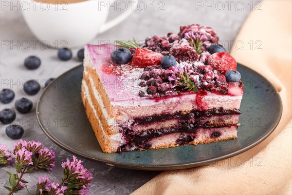 Berry cake with milk cream and blueberry jam on blue ceramic plate with cup of coffee and fresh