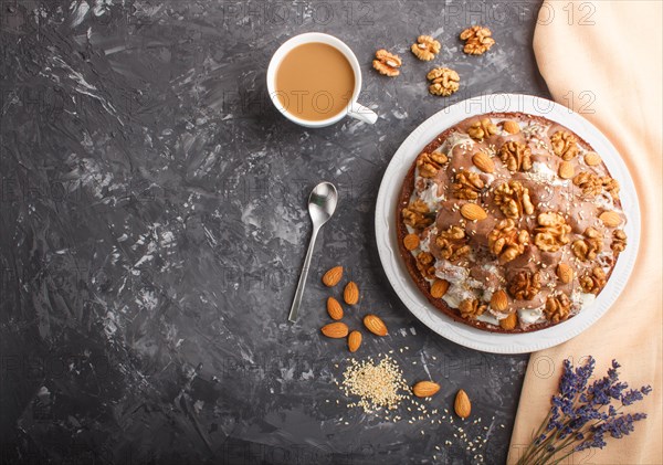 Homemade cake with milk cream, cocoa, almond, hazelnut on a black concrete background with orange