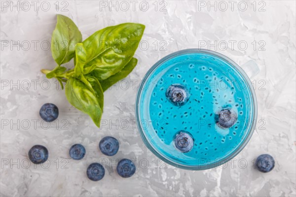 Glass of blueberry blue colored drink with basil seeds on a gray concrete background. Morninig,