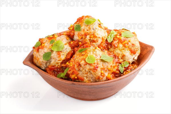 Pork meatballs with tomato sauce, oregano leaves, spices and herbs in clay bowl isolated on white