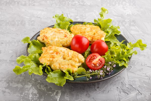 Minced chicken cutlets with lettuce, tomatoes and herbs on a gray concrete background. side view,