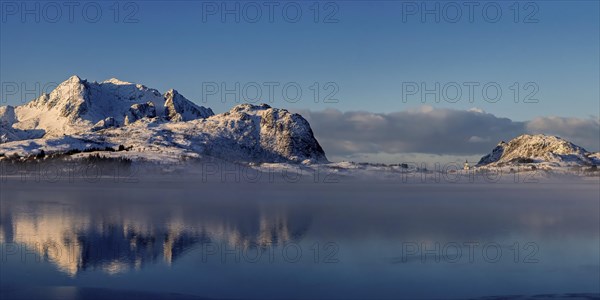 Leichter nebel in der verschneiten Berglandschaft auf den vesteralen mit schoener Spiegelung im