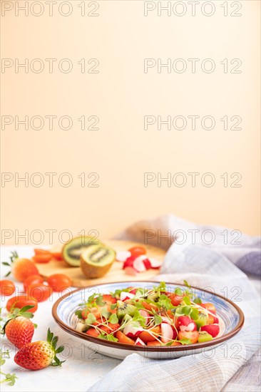 Vegetarian fruits and vegetables salad of strawberry, kiwi, tomatoes, microgreen sprouts on white