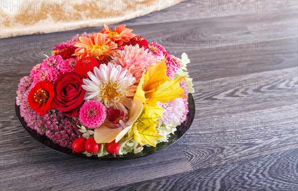 Floral arrangement of autumn flowers on a plate. dahlia, zinnia, rose, orchid, maple leaves. copy