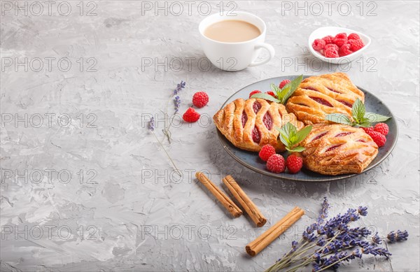 Puff pastry buns with strawberry jam on blue ceramic plate on gray concrete background, cup of