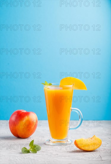 Glass of peach juice on a gray and blue background. Morninig, spring, healthy drink concept. Side
