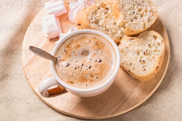 Sweet buns, meringues and coffee cup on a wooden board and linen tablecloth