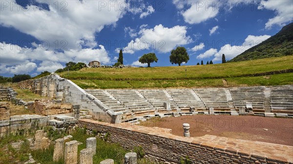 Historic theatre site with tiered rows of seats under a partly cloudy sky, Ancient Theatre,