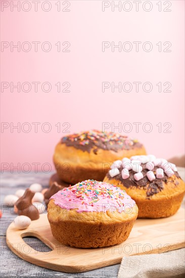 Homemade glazed and decorated easter pies with chocolate eggs and rabbits on a gray and pink